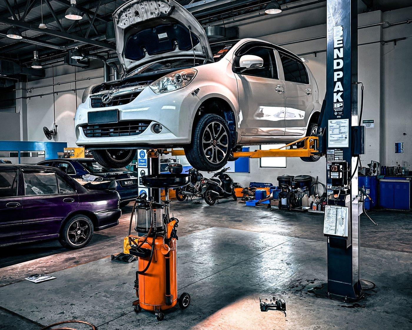 A vehicle raised on a two-post lift inside the repair shop